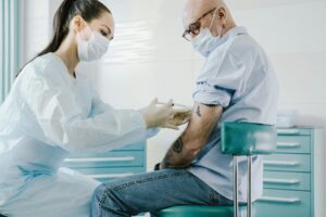 Profissional de saúde aplicando injeção no braço de paciente sentado em clínica