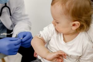 Criança com curativo de vacina no consultório com o médico