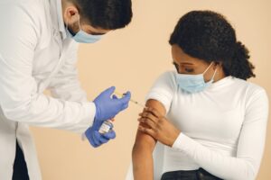 Profissional de saúde aplicando vacina em paciente em clínica de vacinação.